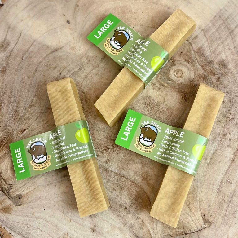 Three large apple treats with green labels on a wooden surface