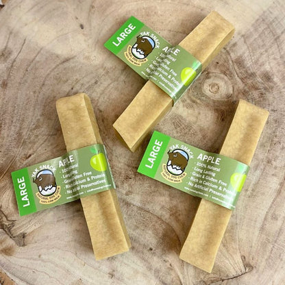 Three large apple treats with green labels on a wooden surface