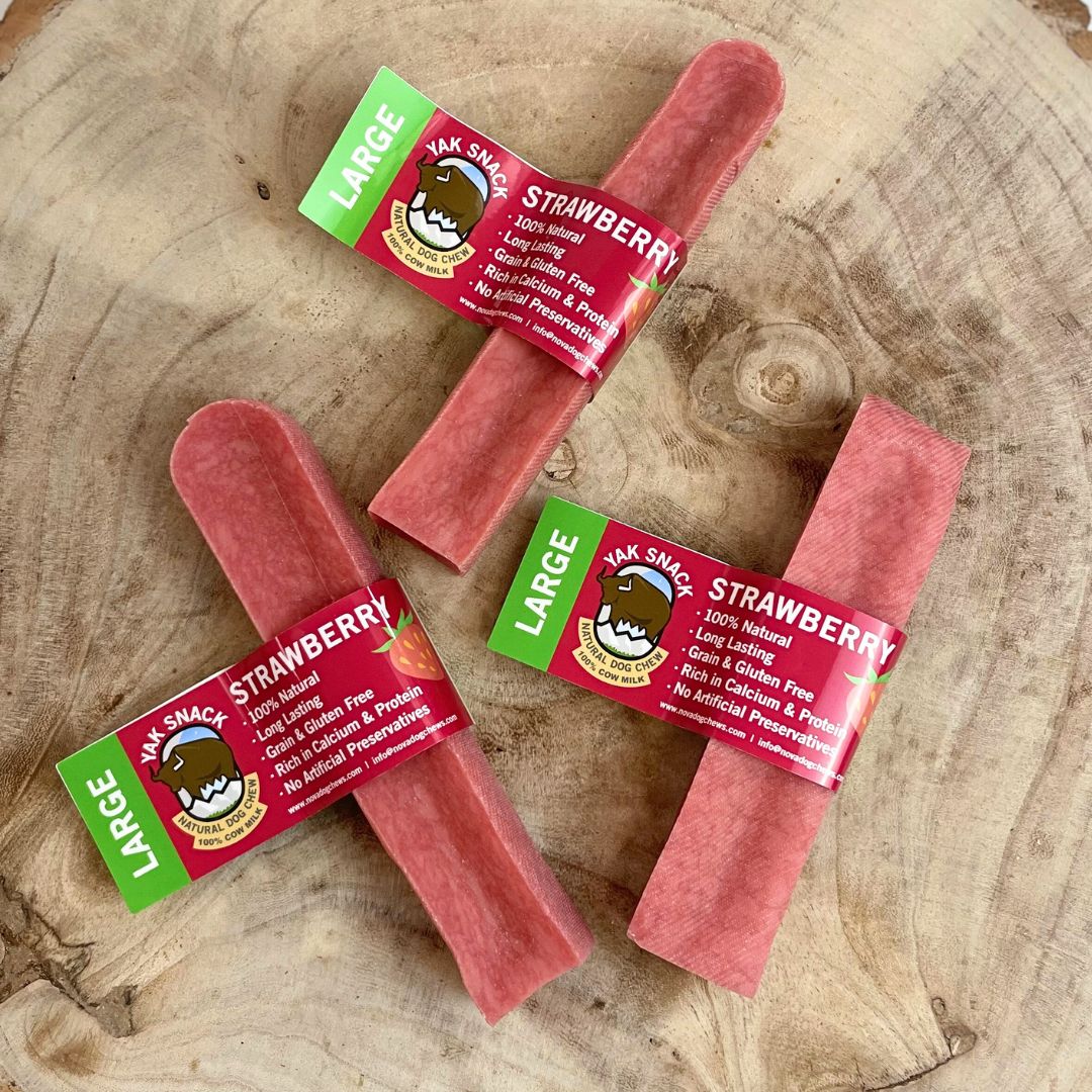 Three strawberry-flavored Yak Snacks on a wooden surface