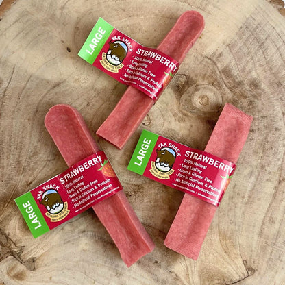 Three strawberry-flavored Yak Snacks on a wooden surface