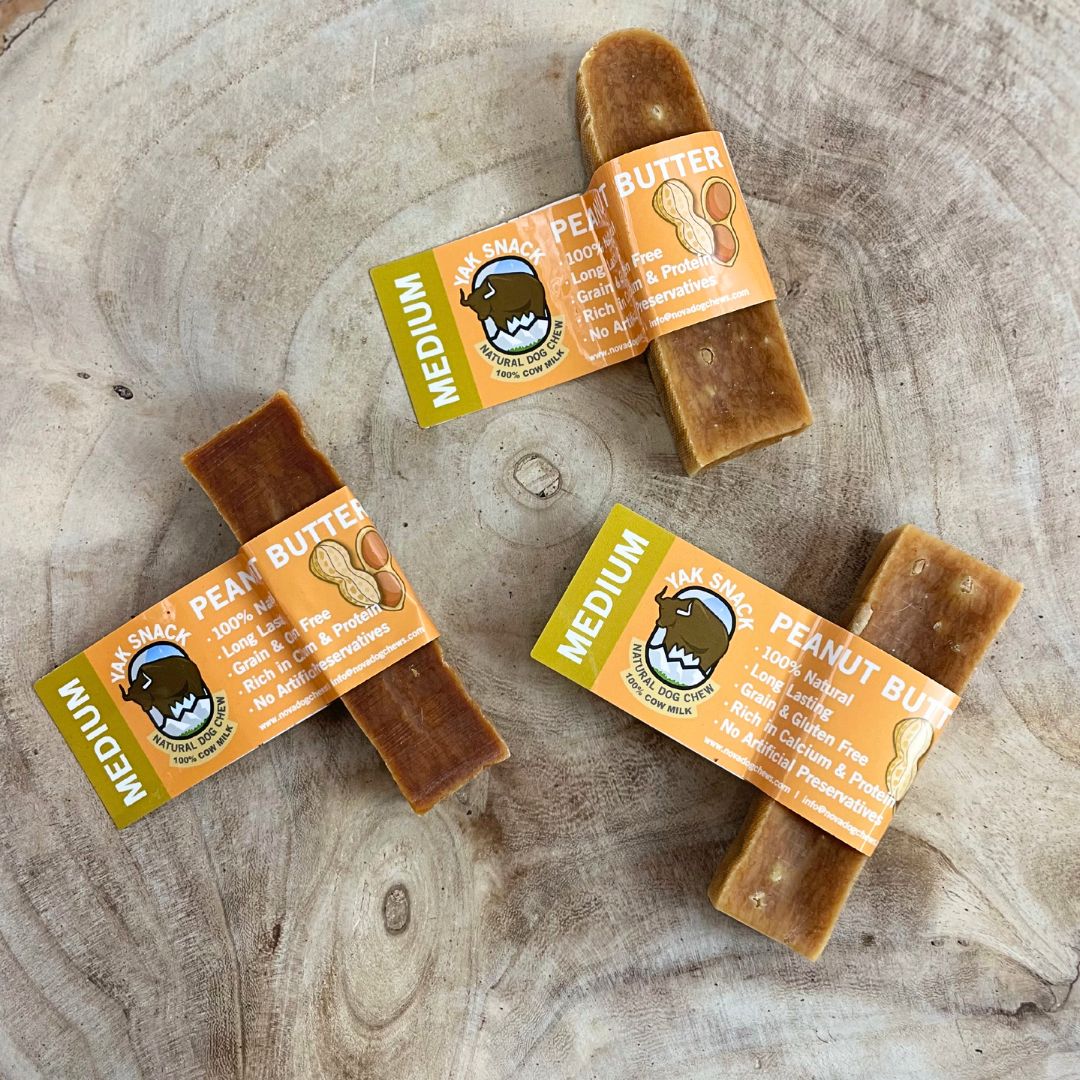 Three packages of Peanut Butter Dog Treats on a wooden surface