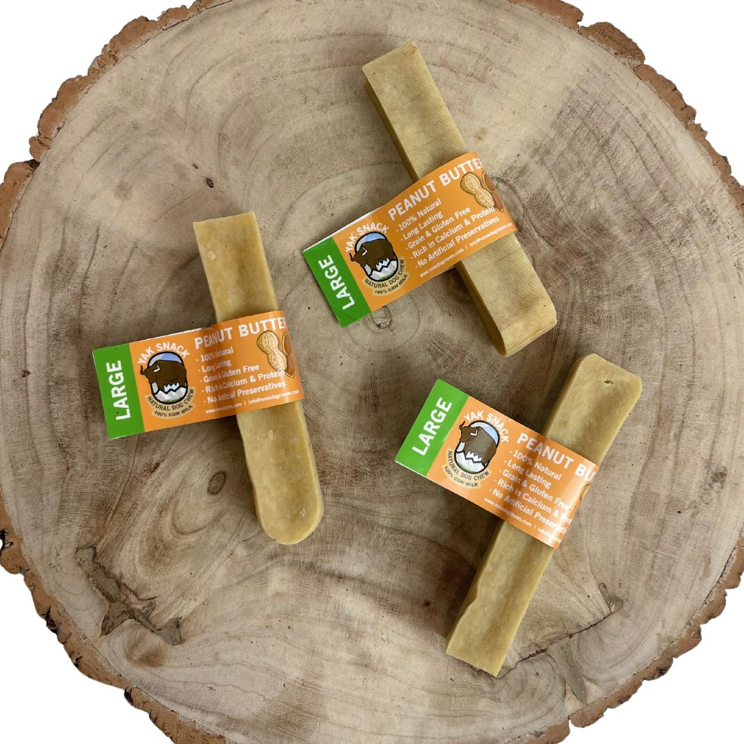 Three large peanut butter dog treats on a wooden surface with visible labels.